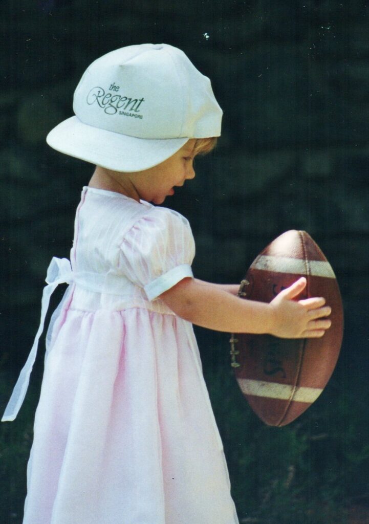 little girl holding a football; family photos; smile; 
